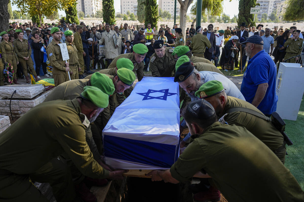 Israeli soldiers lower into the grave the flagged coffin of Staff Sergeant Aschalwu Sama during ...