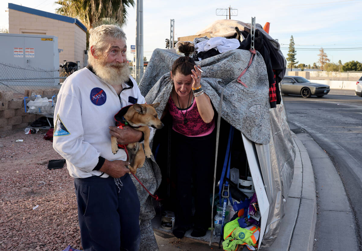 Robert Tully, 62, holds “Brody” who belongs to Audrey Cook, 35, at their encampme ...