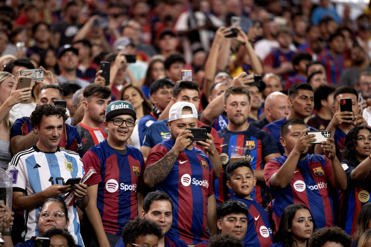 Barcelona fans record and watch as their team has a corner kick during the second half of a Soc ...
