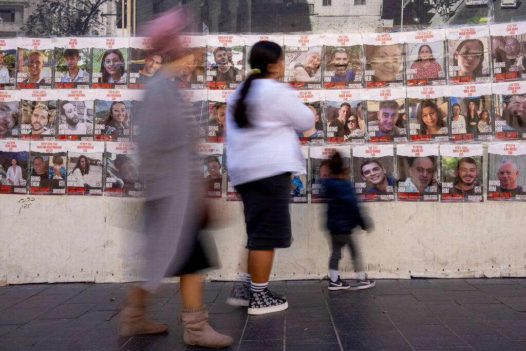 People walk past a wall with photos of the hostages who are believed to remain captive in the G ...