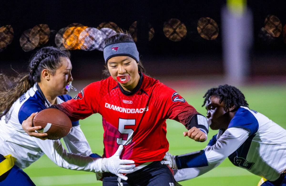 Desert Oasis quarterback Akemi Higa (5) looks to gets through Shadow Ridge defenders Jaylani Pa ...