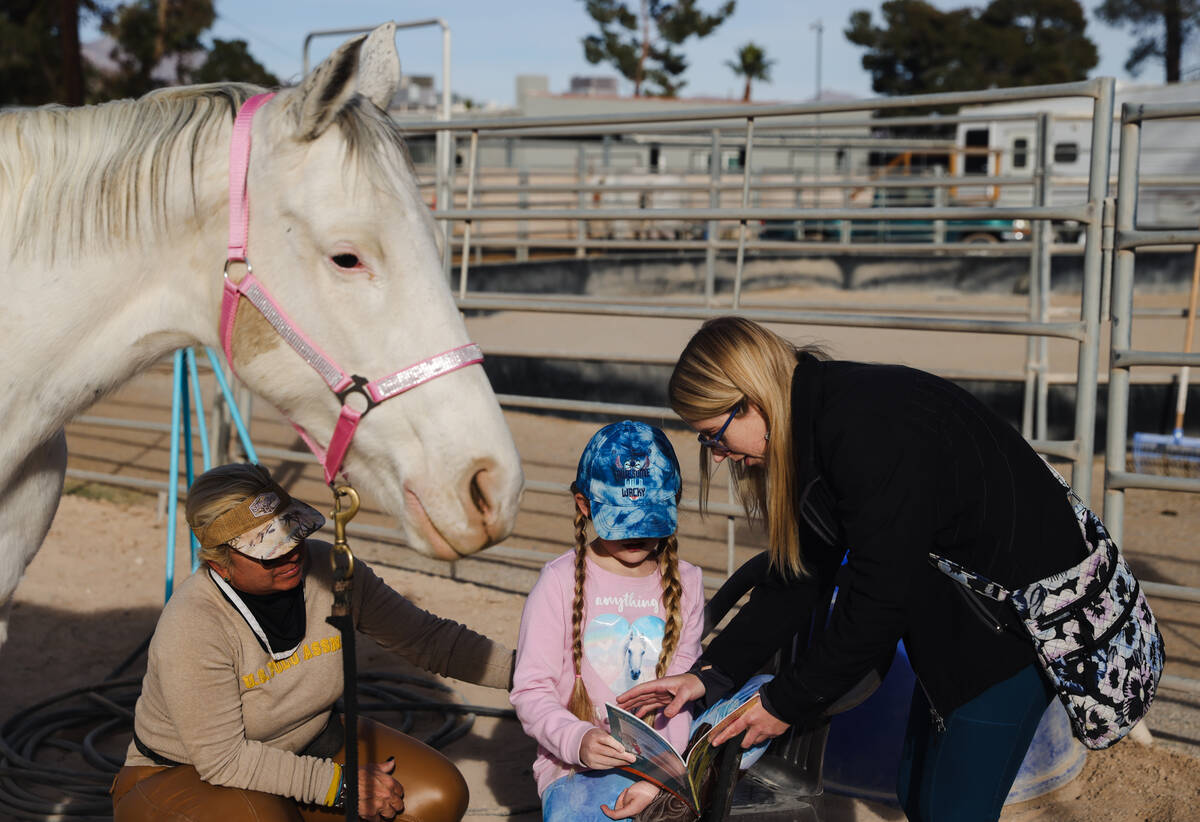 Eliora Oles, 9, reads to Lagertha with help from her mom Kelly Oles, right, and Esther Hillner, ...