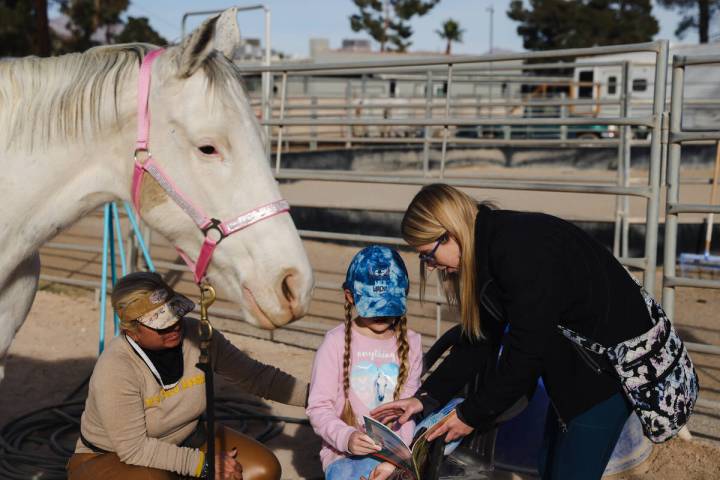 Eliora Oles, 9, reads to Lagertha with help from her mom Kelly Oles, right, and Esther Hillner, ...