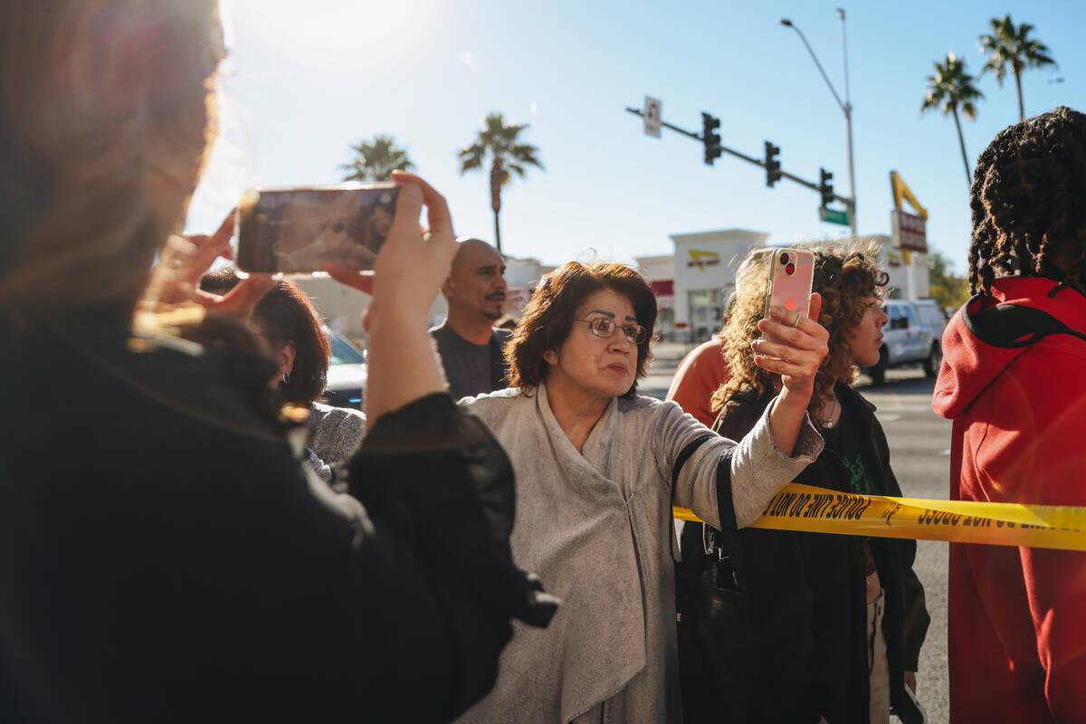 People record and listen to the police at the scene of a shooting on the UNLV campus on Wednesd ...