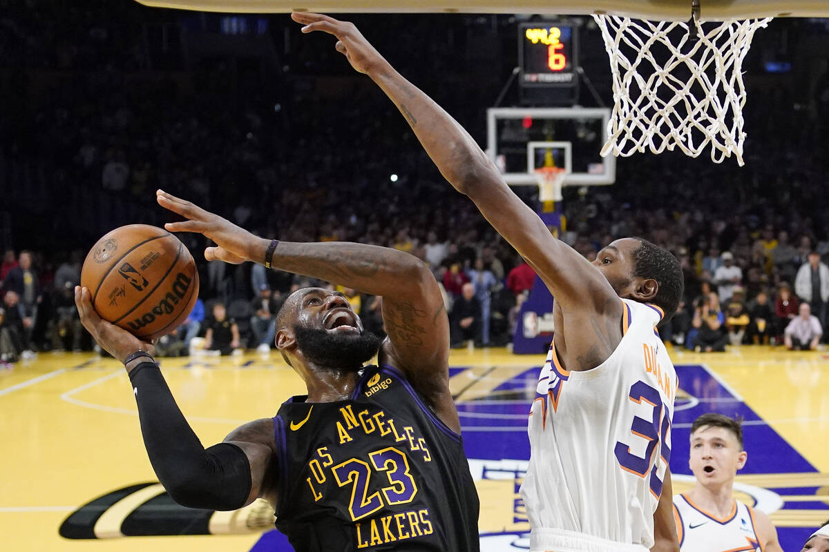 Los Angeles Lakers forward LeBron James, left, shoots as Phoenix Suns forward Kevin Durant defe ...