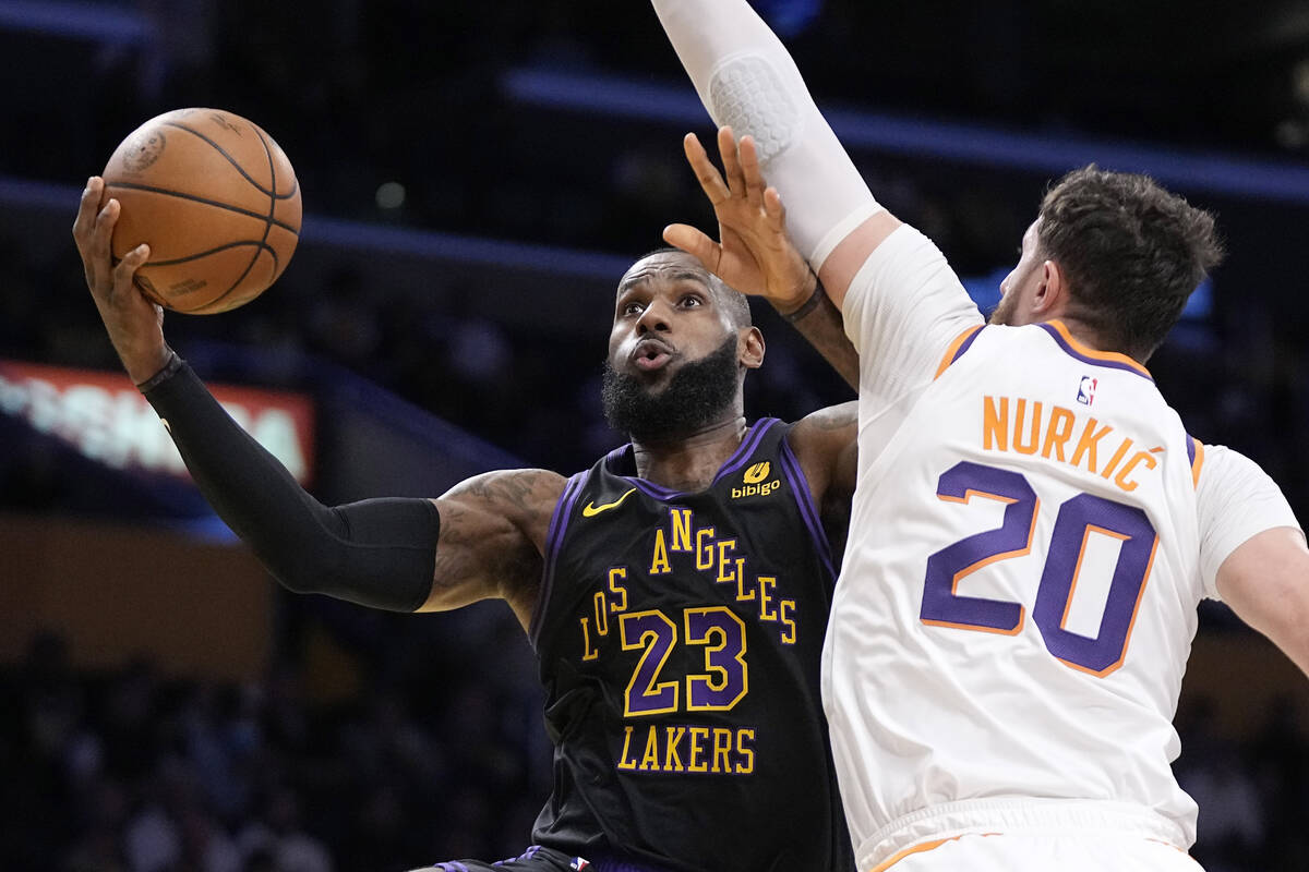 Los Angeles Lakers forward LeBron James, left, shoots as Phoenix Suns center Jusuf Nurkic defen ...