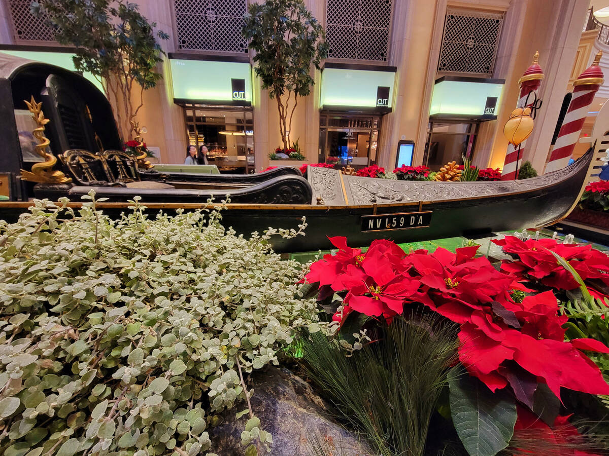 Poinsettias, jumbo pinecones and greenery surround an antique gondola in the Waterfall Atrium a ...