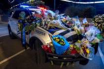 A patrol vehicle is covered in flowers dedicated to Nevada Highway Patrol troopers Sgt. Michael ...