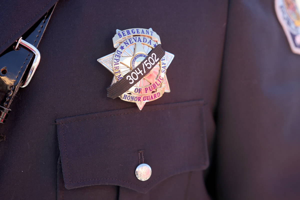 Sgt. Loy Hixson dons a black band on his badge for the memorial for Nevada Highway Patrol troop ...
