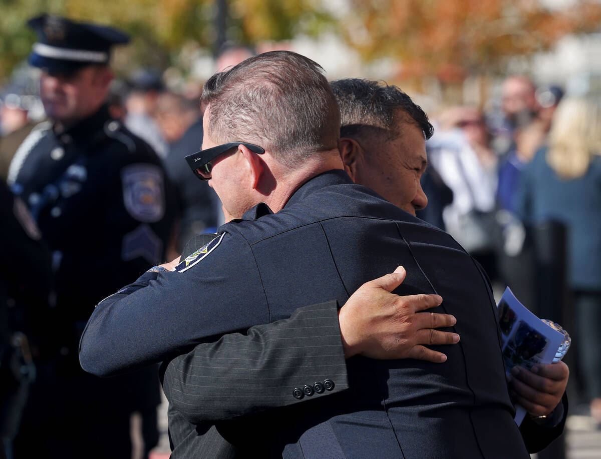 A law enforcement officer hugs a loved one of Nevada Highway Patrol trooper Alberto Felix durin ...