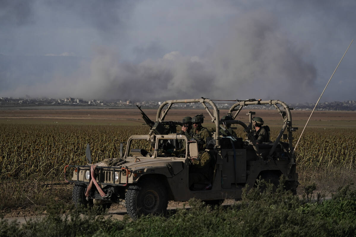 Israeli soldiers patrol as the smoke rises from the Gaza Strip after Israeli strikes on Saturda ...