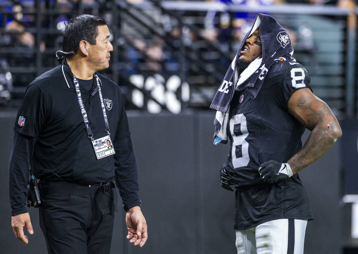 Raiders running back Josh Jacobs (8) is escorted off the field by Dr. Michael Miao, a team orth ...