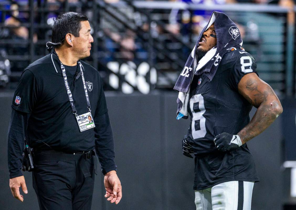 Raiders running back Josh Jacobs (8) is escorted off the field by Dr. Michael Miao, a team orth ...
