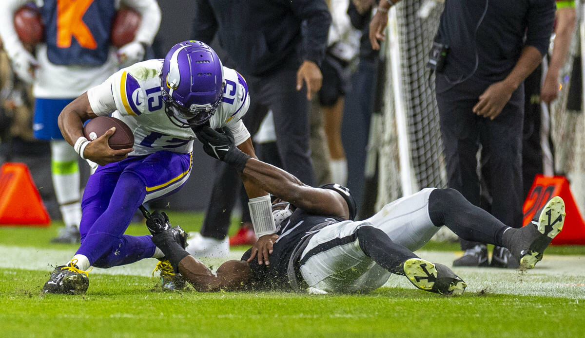 Minnesota Vikings quarterback Joshua Dobbs (15) is pulled down after a run by Raiders cornerbac ...
