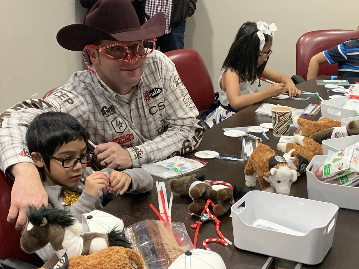 Team roper Coleman Proctor shows off his candy-cane glasses while youngster Sine Tatiano works ...