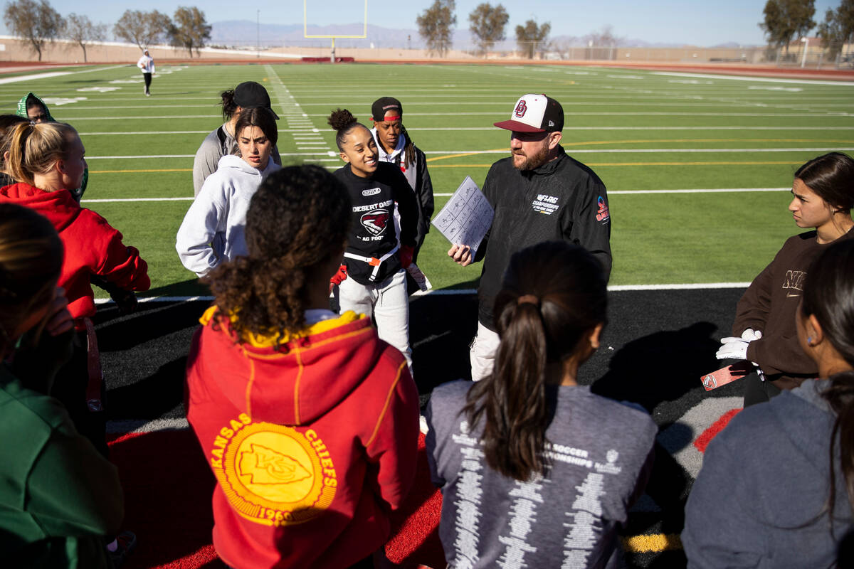 Players huddle with head coach Todd Thomson during a flag football practice at Desert Oasis Hig ...