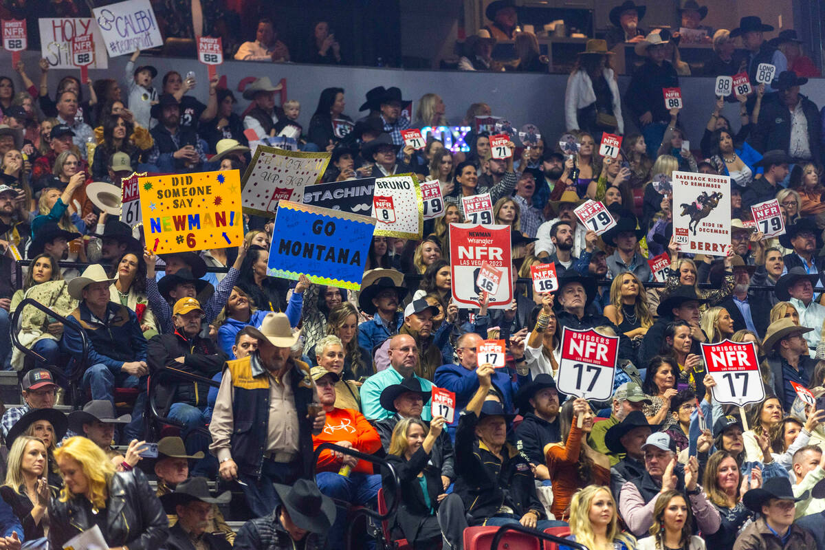Fans hold signs for their favorite competitors during the final day action of the NFR at the Th ...