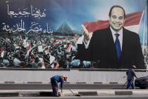 Workers clean the street under a billboard supporting Egyptian President Abdel Fattah el-Sissi ...