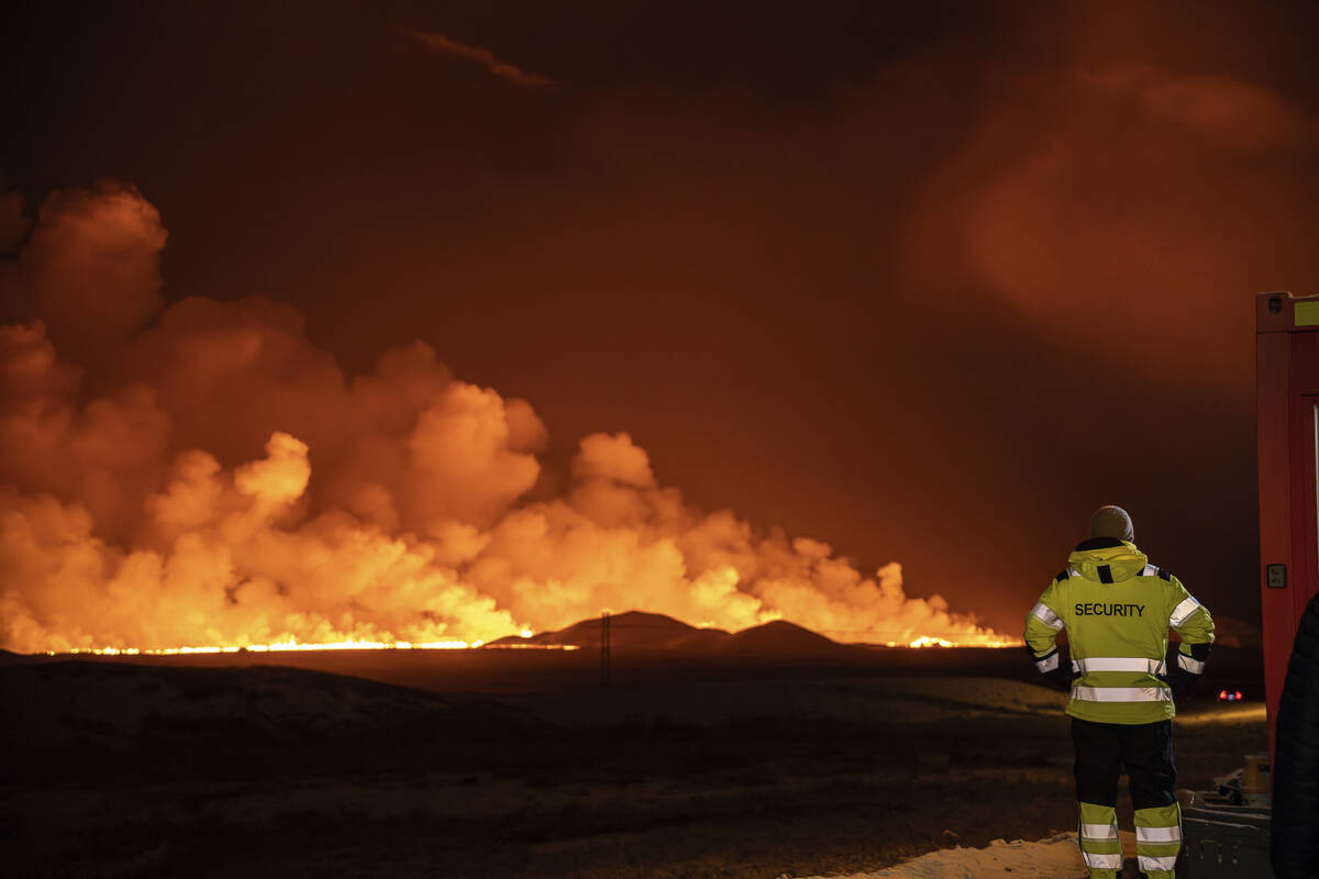A volcanic eruption is seen, turning the sky orange, in Grindavik on Iceland's Reykjanes Penins ...