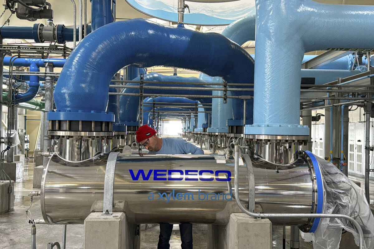 A worker cleans an ultraviolet light disinfection system as part of a water purification proces ...