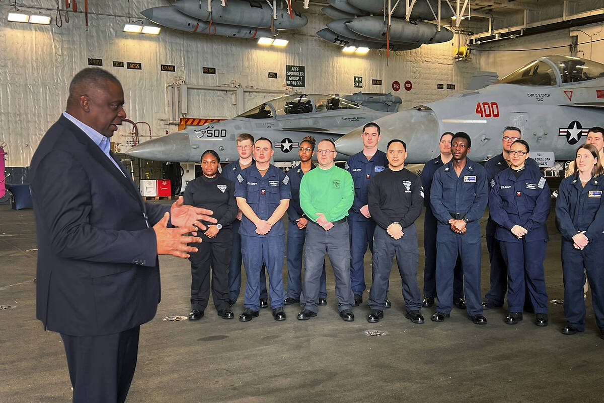 Defense Secretary Lloyd Austin, left, talks to crew members of the USS Gerald R. Ford during an ...