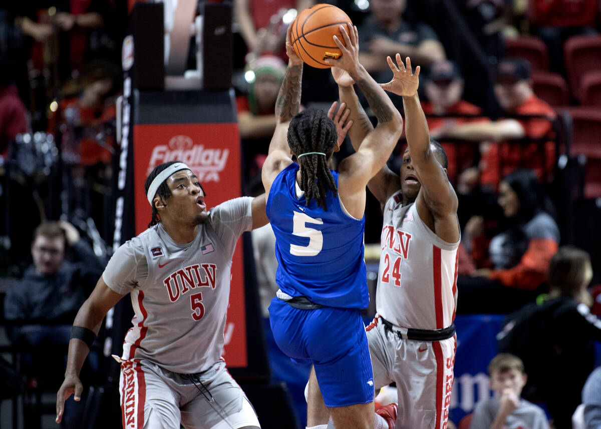 Hofstra Pride guard Jaquan Carlos (5) shoots with pressure from UNLV Rebels forward Rob Whaley ...
