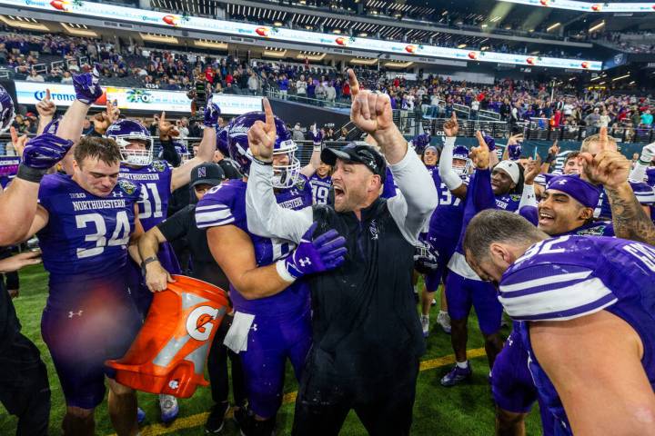 Northwestern Wildcats head coach David Braun celebrates their win after being doused with sport ...