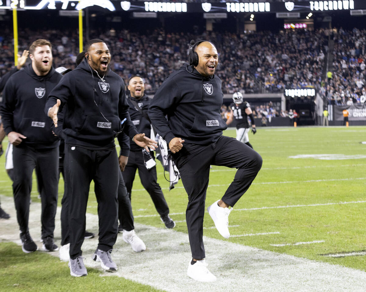 Raiders head coach Antonio Pierce, right, high-steps to celebrate as defensive tackle John Jenk ...