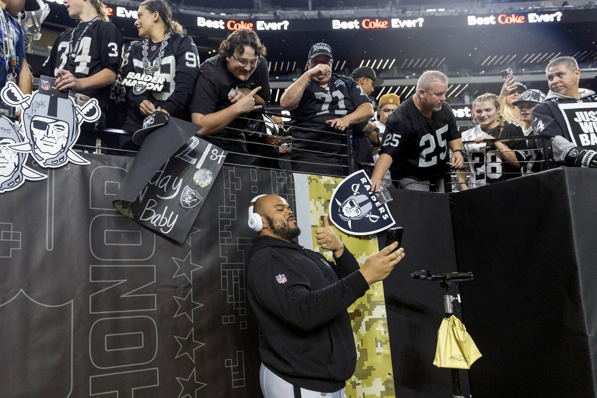 Raiders offensive tackle Jermaine Eluemunor (72) takes a selfie with fans before an NFL game ag ...