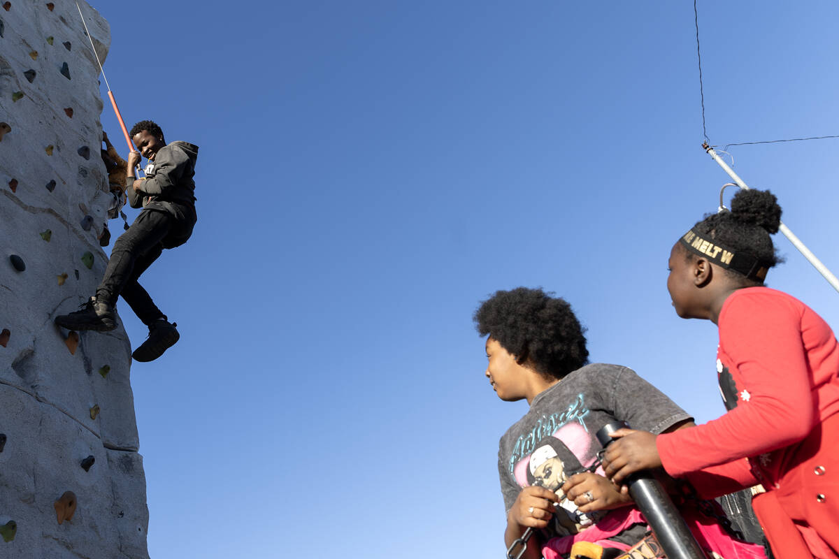 Tremonte Gravely, 13, climbs a rock wall during a Christmas block party organized by Take Back ...