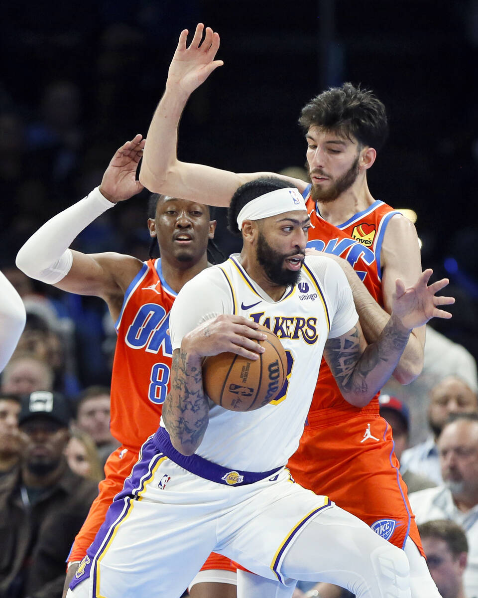 Los Angeles Lakers forward Anthony Davis, front, takes the ball past Oklahoma City Thunder forw ...