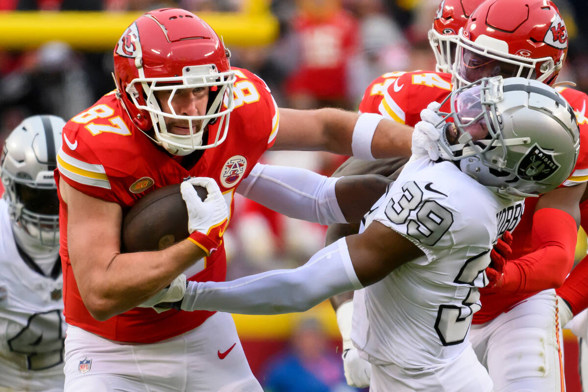Kansas City Chiefs tight end Travis Kelce (87) fights off a tackle by Las Vegas Raiders cornerb ...
