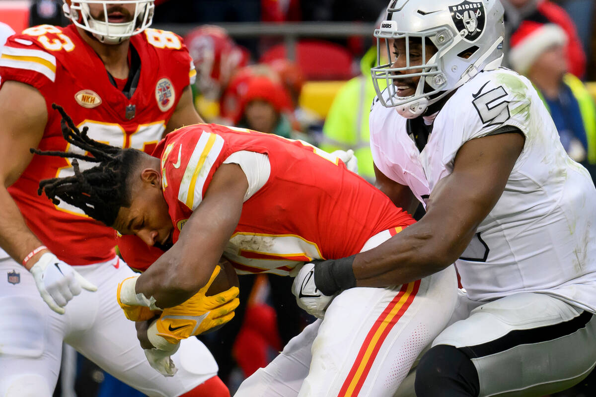 Kansas City Chiefs running back Isiah Pacheco, left, loses his helmet while being tackled by La ...
