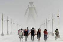 Burning Man visitors walk through dust at the annual Burning Man event on the Black Rock Desert ...