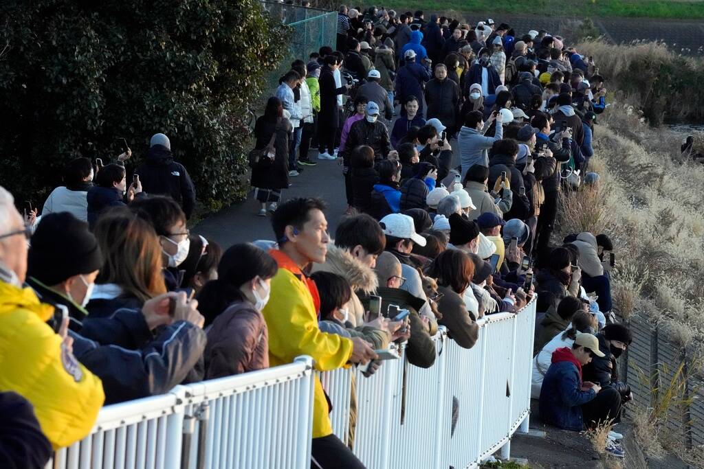 People observe the first sunrise on New Year's Day from a pedestrian bridge, Monday, Jan. 1, 20 ...