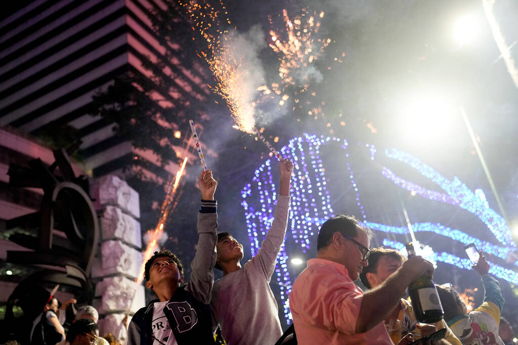 People celebrate New Year at Plaza Altamira in Caracas, Venezuela, early Monday, Jan. 1, 2024. ...