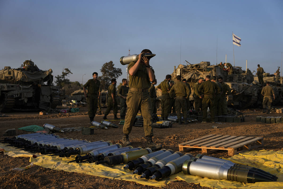 Israeli soldiers load shells onto a tank at a staging area in southern Israel near the border w ...
