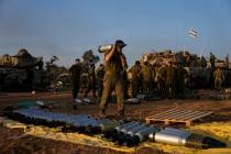 Israeli soldiers load shells onto a tank at a staging area in southern Israel near the border w ...