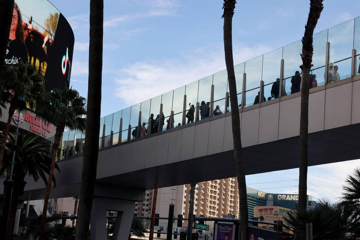 People walk across a pedestrian bridge over the Strip at Harmon Avenue in Las Vegas on Tuesday, ...
