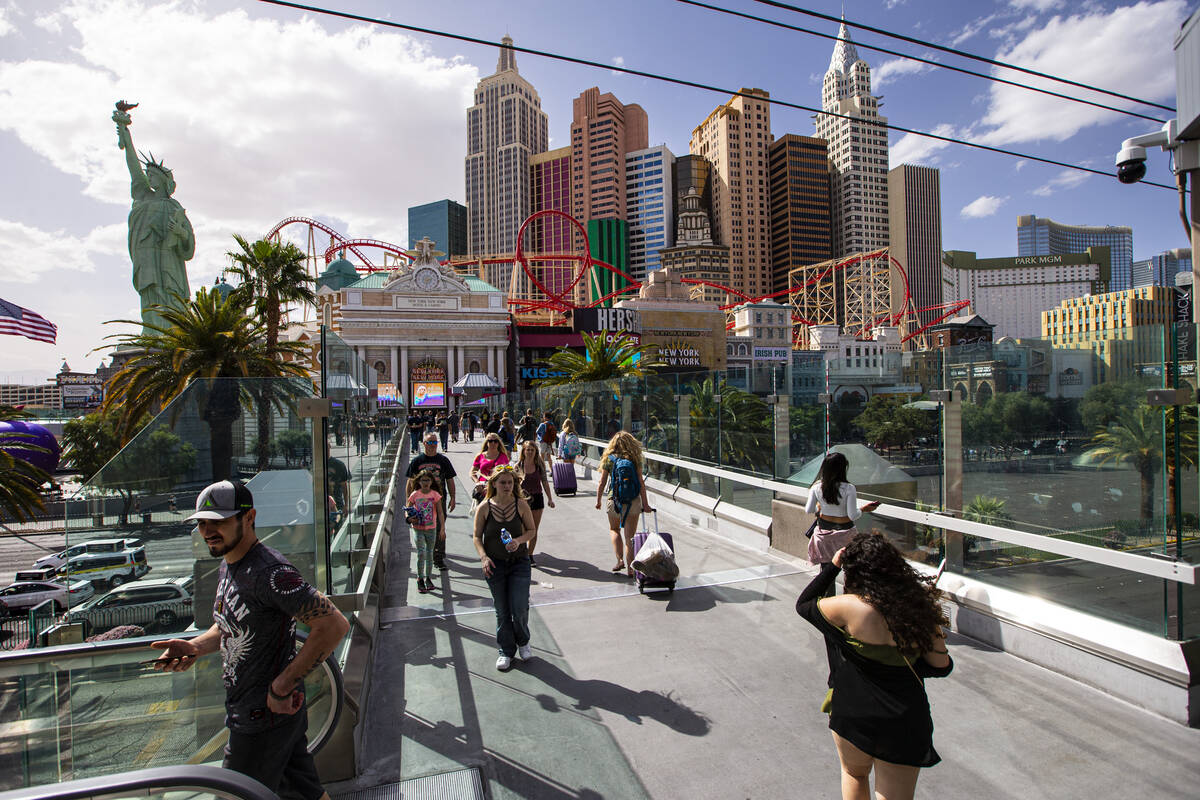 People walk along the pedestrian bridge between the New York-New York and the MGM Grand on Marc ...