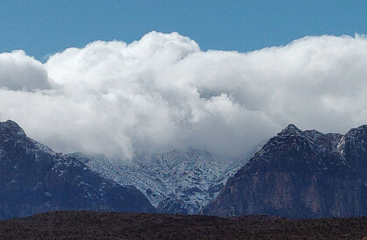 Clouds hug the mountains after snow fell on the foothills of the Spring Mountains just west of ...