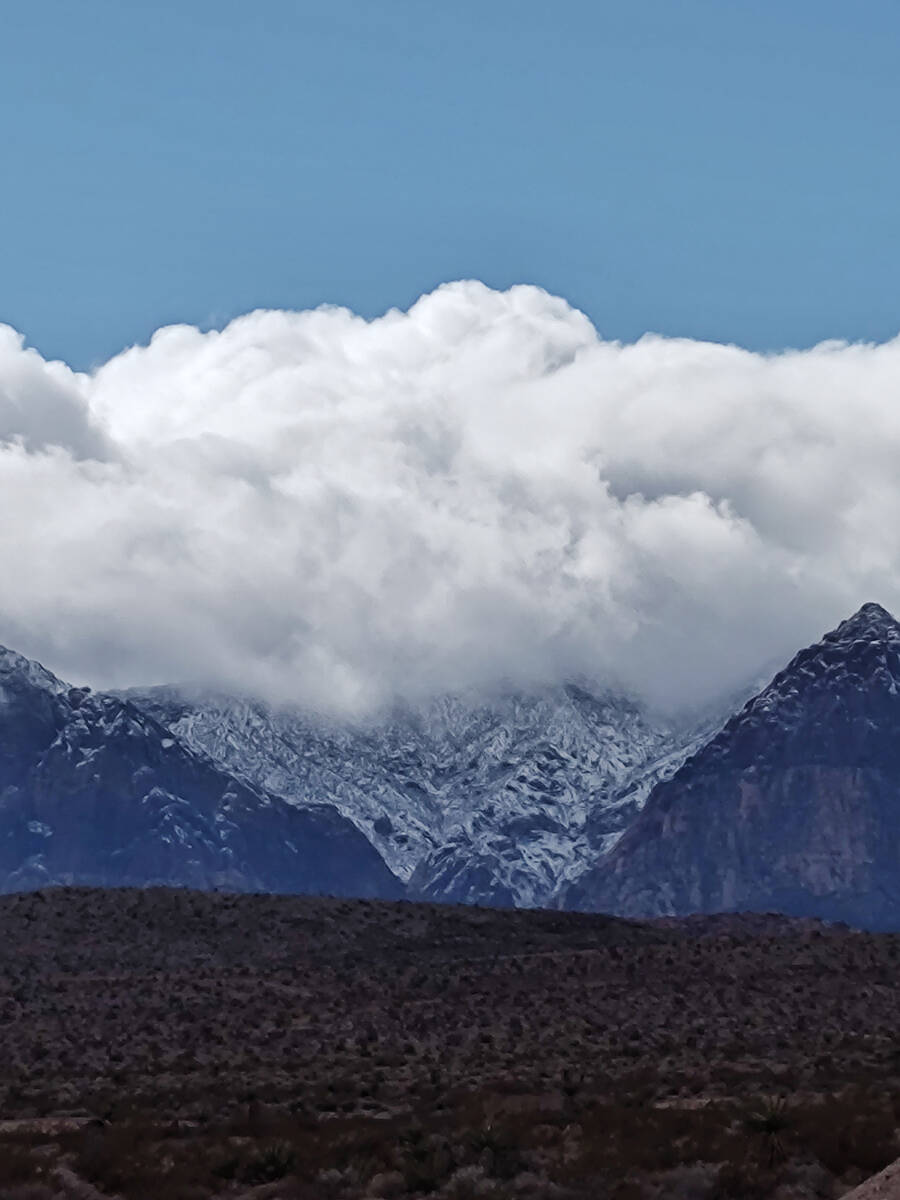 Clouds hug the mountains after snow fell on the foothills of the Spring Mountains just west of ...