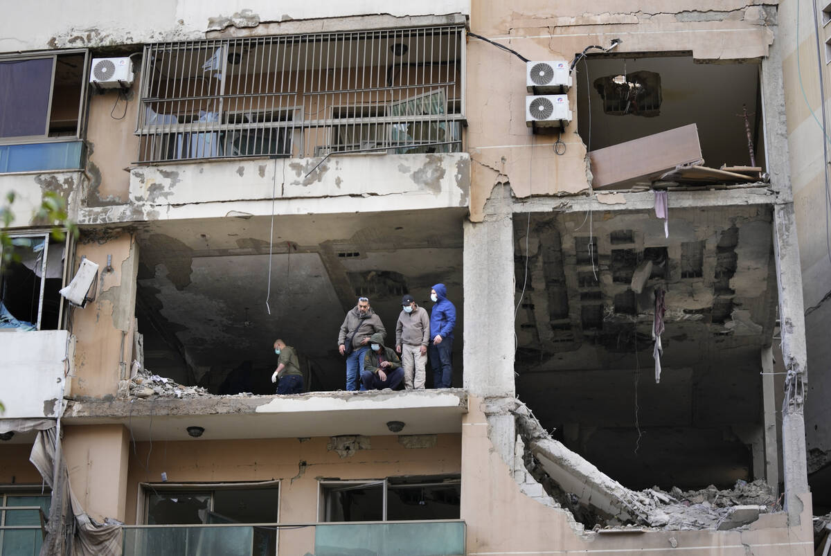 Investigators stand on an apartment building where an apparent Israeli strike Tuesday killed to ...