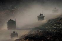 A convoy of Israeli troops moves in the Gaza Strip as seen from southern Israel, Thursday, Jan. ...
