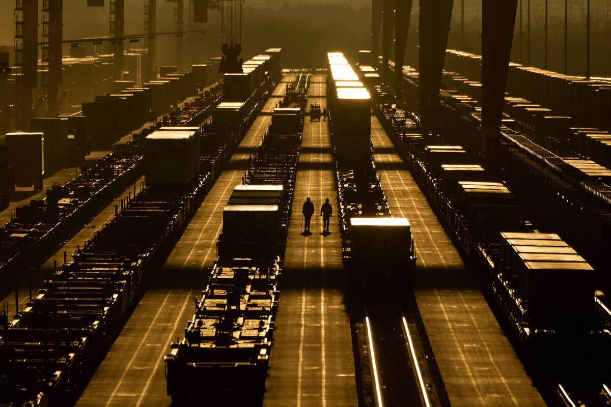 Workers walk among shipping containers at a BNSF intermodal terminal, Wednesday, Jan. 3, 2024, ...