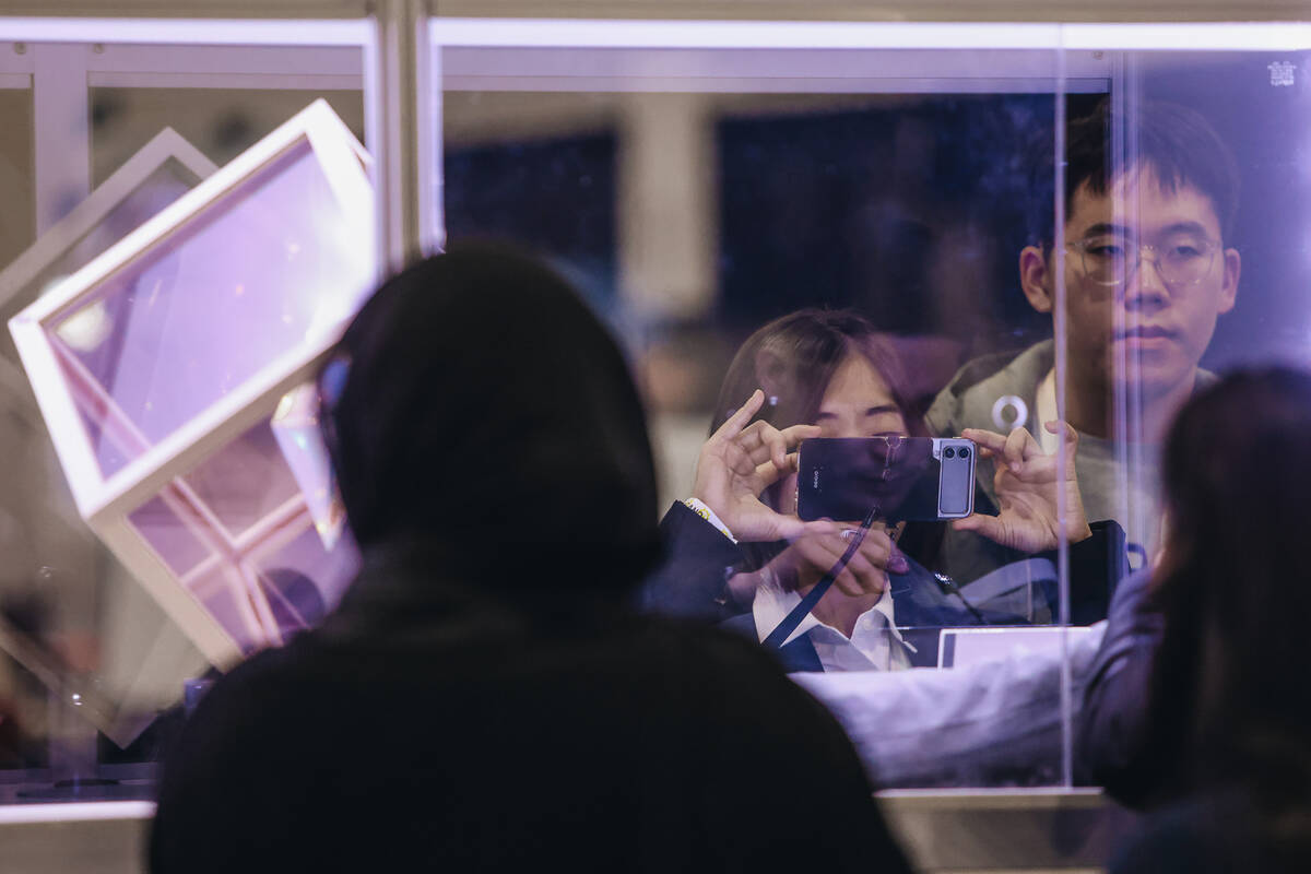 A peson takes a photograph of the inside of a booth during CES Unveiled at the Mandalay Bay Con ...