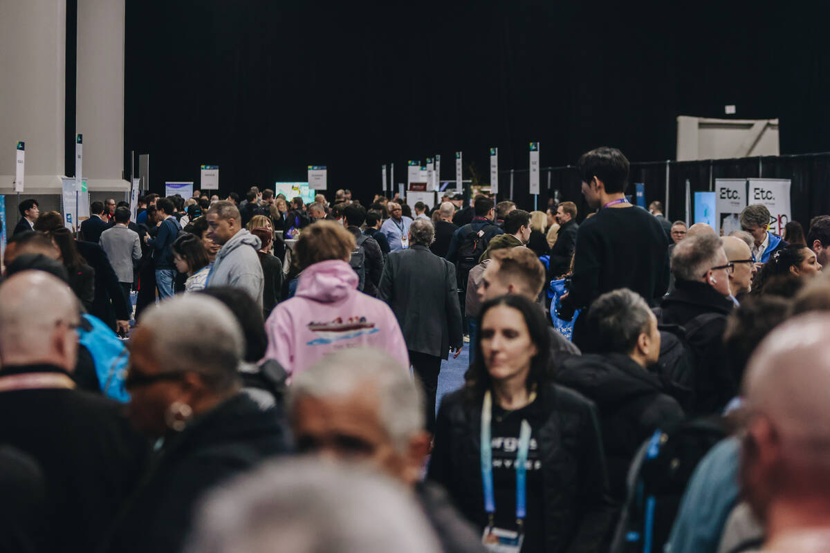 People walk down rows of booths and look at different technology pieces during CES Unveiled at ...