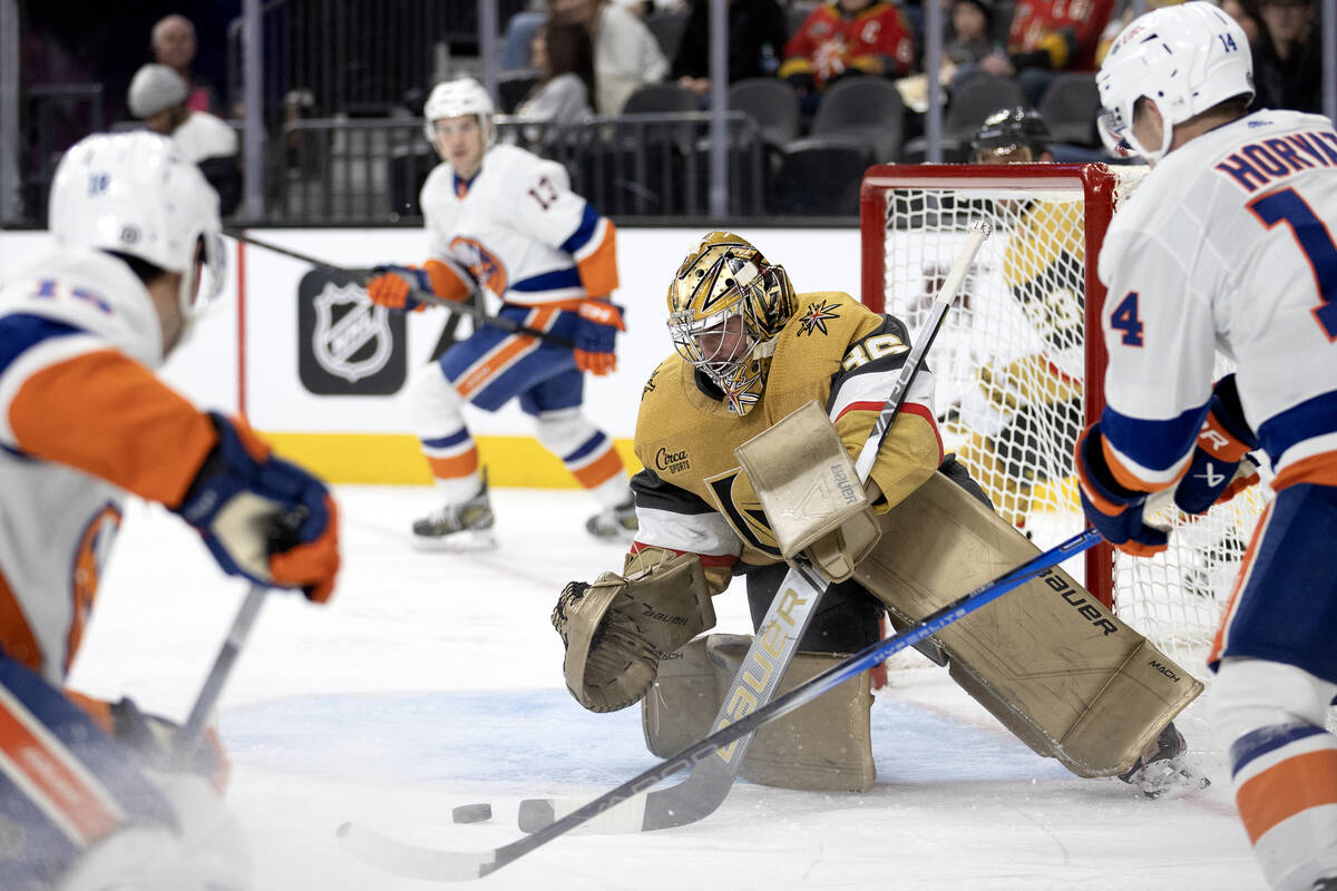 Golden Knights goaltender Logan Thompson (36) saves the puck while surrounded by the Islanders ...