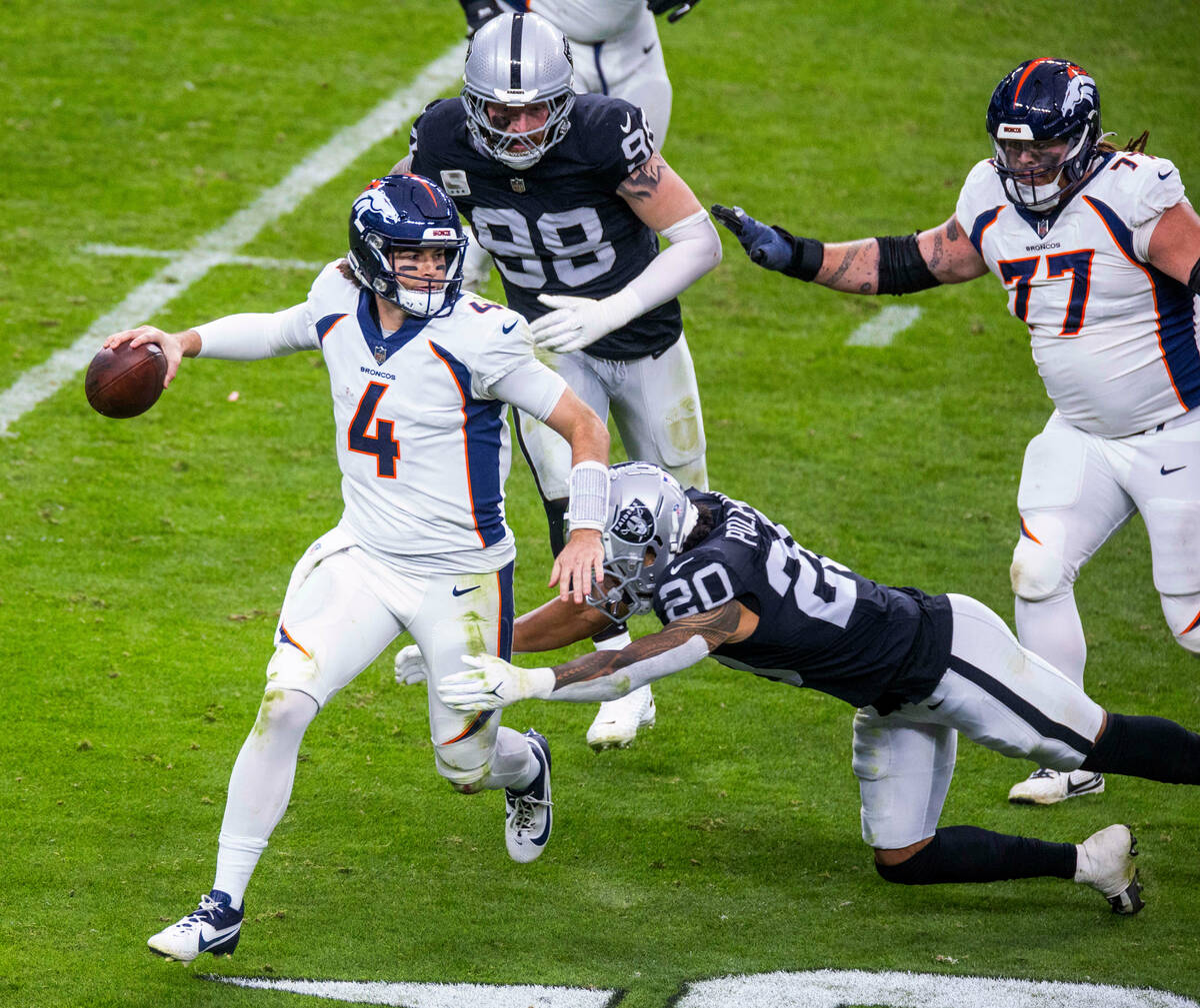 Denver Broncos quarterback Jarrett Stidham (4) is sacked by Raiders safety Isaiah Pola-Mao (20) ...