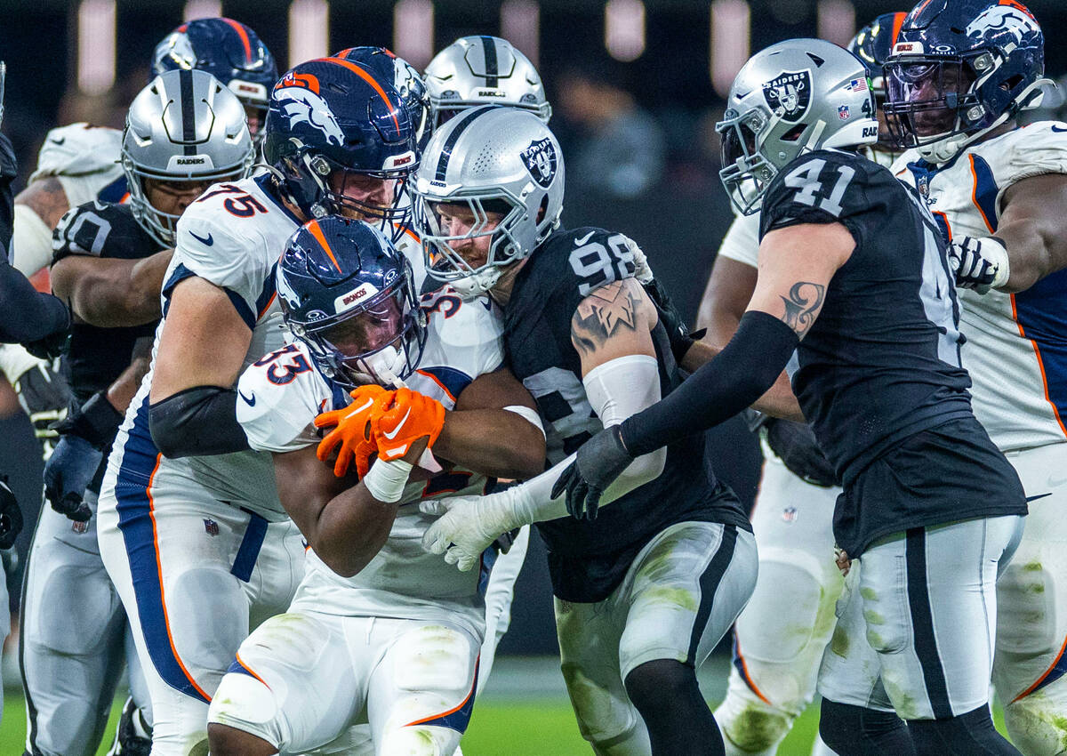 Denver Broncos running back Javonte Williams (33) is wrapped up by Raiders defensive end Maxx C ...